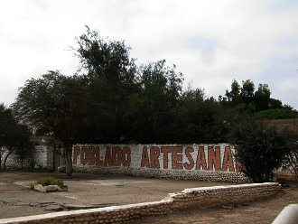 Ein Graffiti kndigte das
                            Kunsthandwerkerdorf an ("Poblado
                            artesanal")