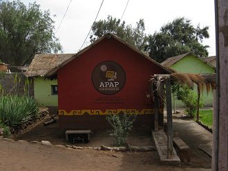Kunsthandwerkerdorf von Arica, mit dem
                            Logo der APAP und mit mit Webseite und
                            E-Mail an der Hausfassade