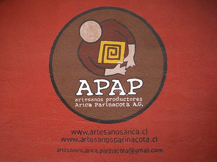 Das Logo der
                            "Kunsthandwerkproduzenten Arica
                            Parinacota A.G." ("Artesanos
                            productores Arica Parinacota A.G."),
                            die Webseite und das E-Mail, Nahaufnahme