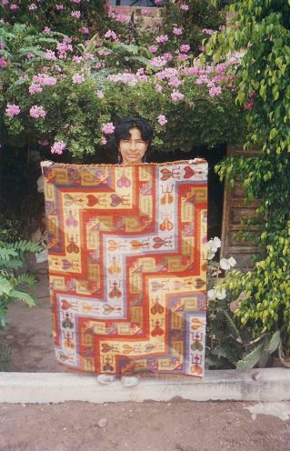 Frau Gallardo zeigt einen ihrer gewebten
                        Wandteppiche (tejido)