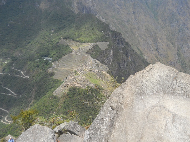 Machu Picchu, Hausberg Huaynapicchu,
                    geschnittene Gigasteine auf dem Gipfel und die
                    Aussicht auf Machu Picchu