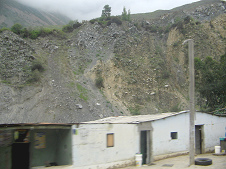 Weisses Haus am Strassenrand im
                        Huaytara-Tal mit Felswand im Hintergrund