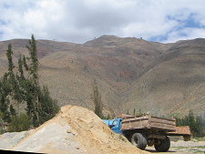 Lastwagen hinter einem Sandhaufen und Sicht
                        auf Berge
