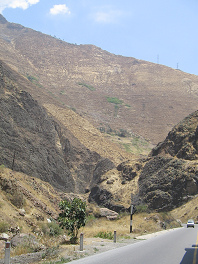 Steiler Berghang mit Strommasten oben
                        drauf